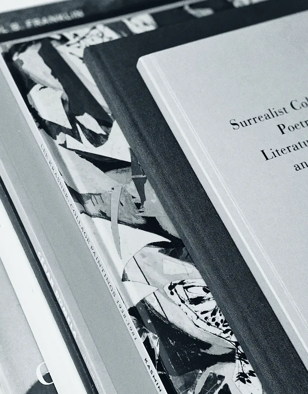 Art books stacked open, with black-and-white collage artwork and a title page on Surrealist poetry
