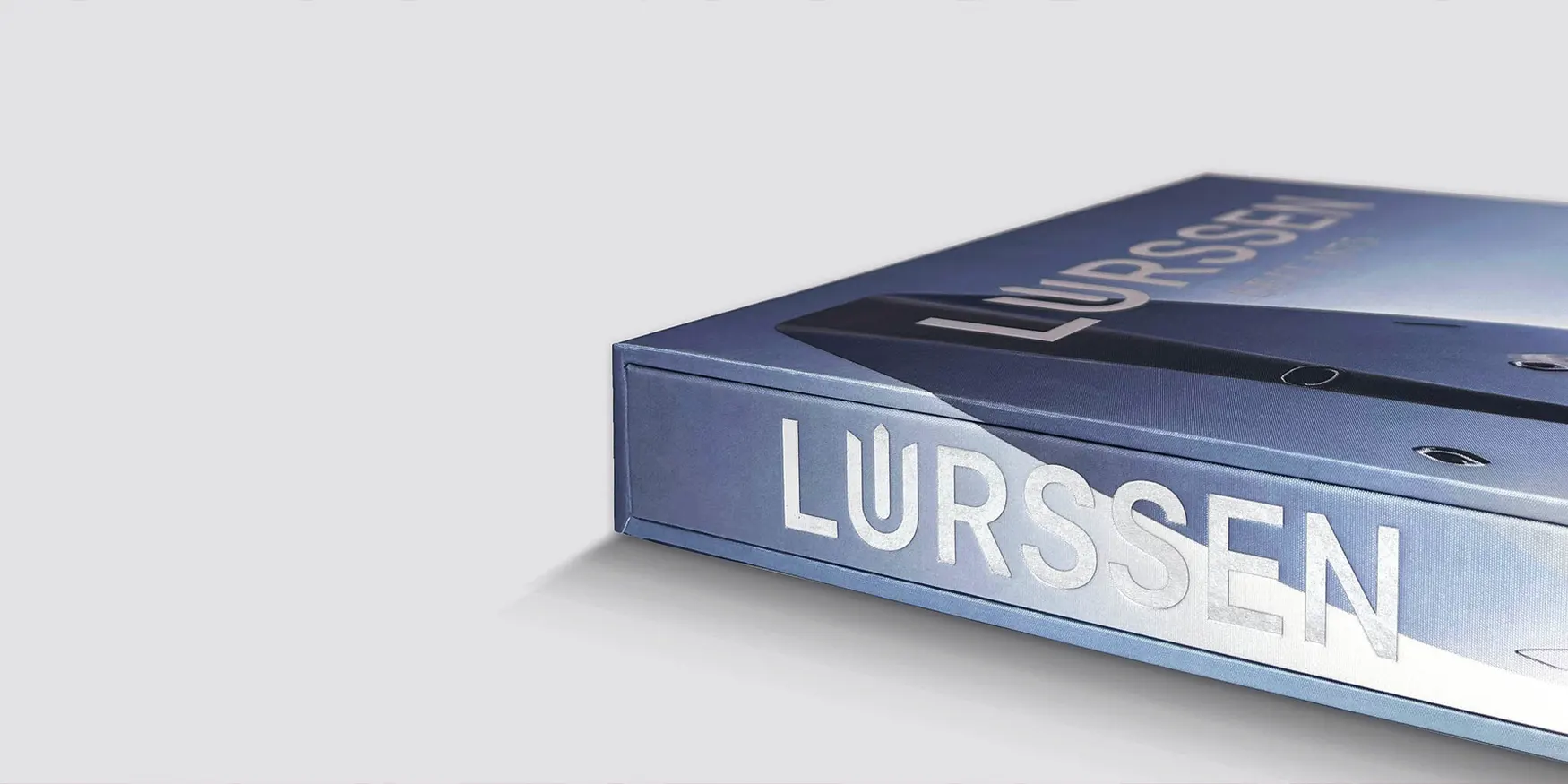 Lürssen book in a blue-grey case with LÜRSSEN in silver lettering on the cover and spine