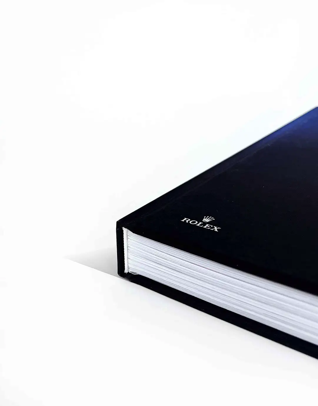 Rolex book with a navy cover, seen from the corner with the page block visible